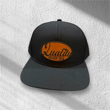 Load image into Gallery viewer, Black cap with orange 'Quality Ready Mix' logo on a textured white background
